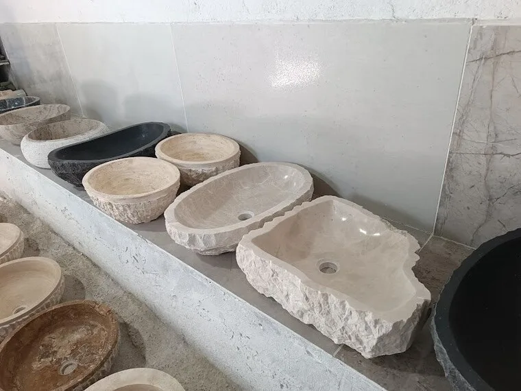 Round travertine basins in several sizes on a workshop shelf